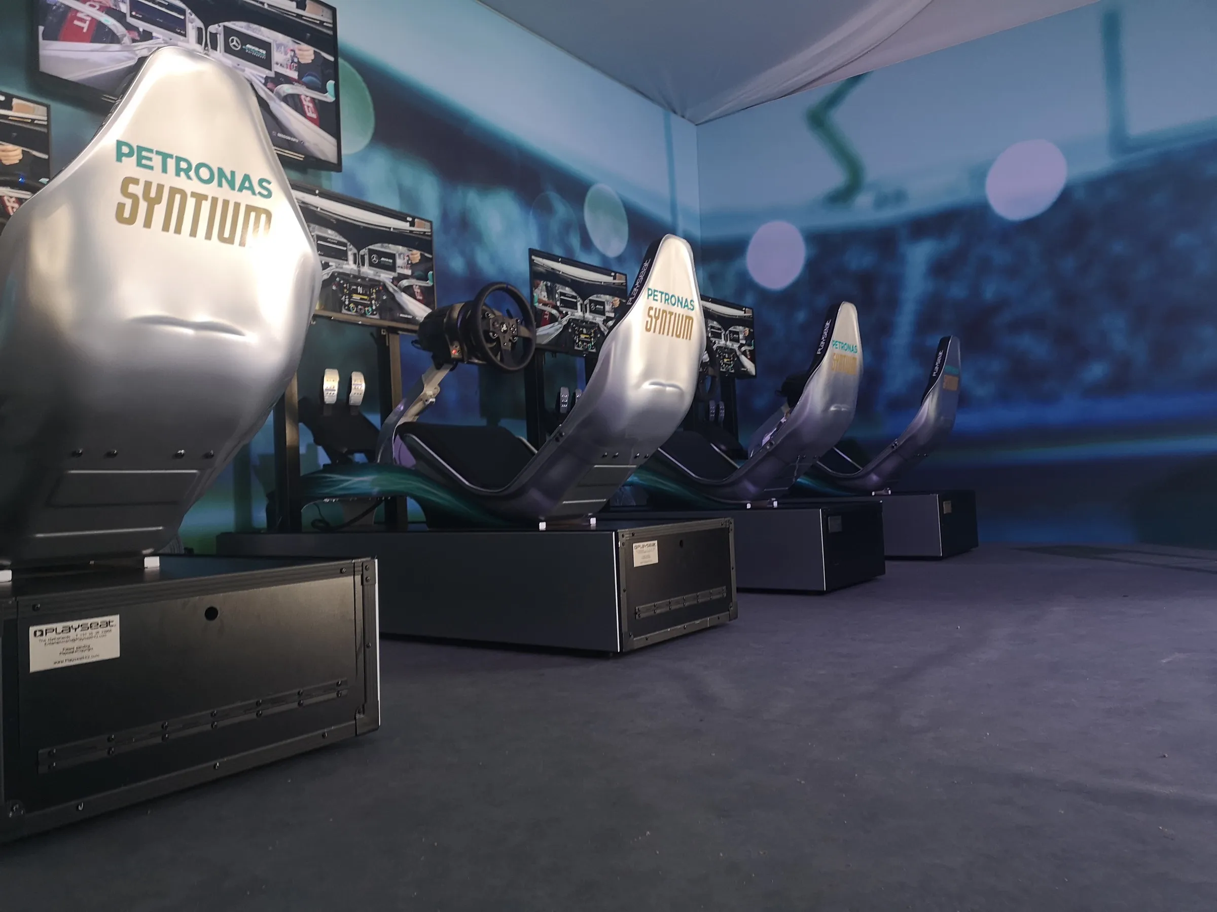Row of silver brand-wrapped racing simulators lined up at an event