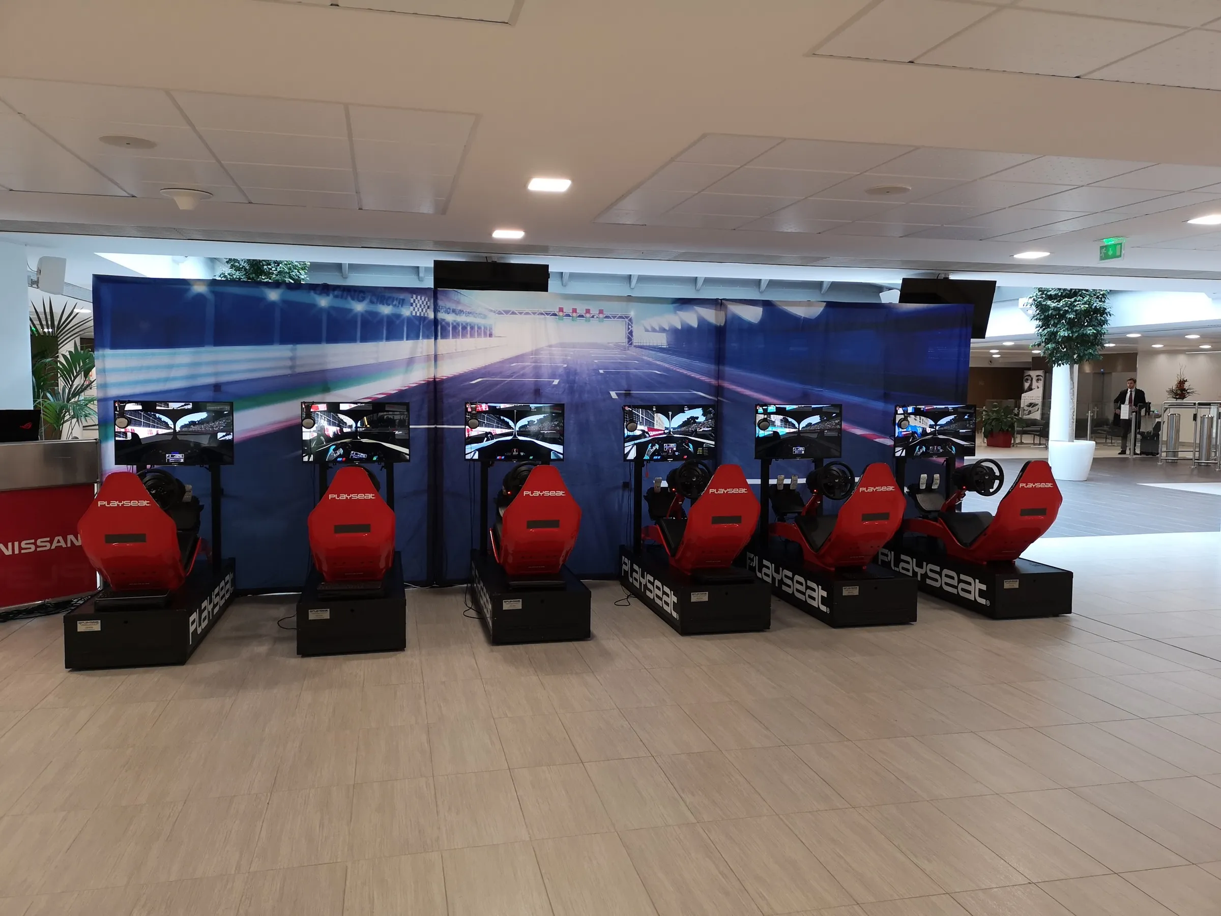 Six networked racing simulators in a branded grid at a corporate event