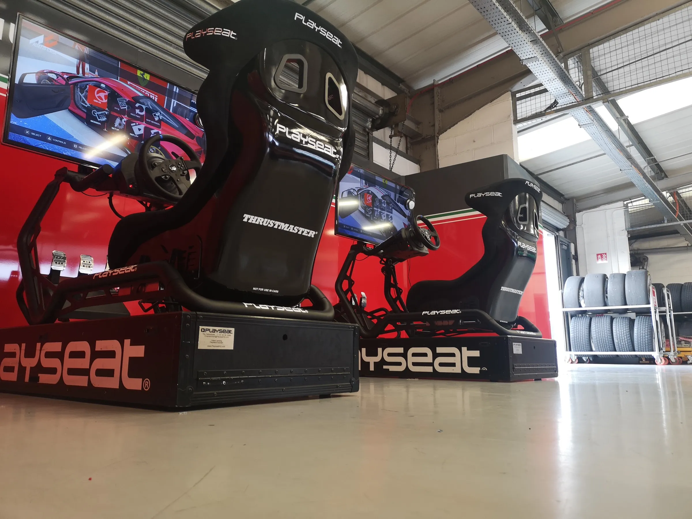 Black racing simulators with red branding set up in a garage at Silverstone