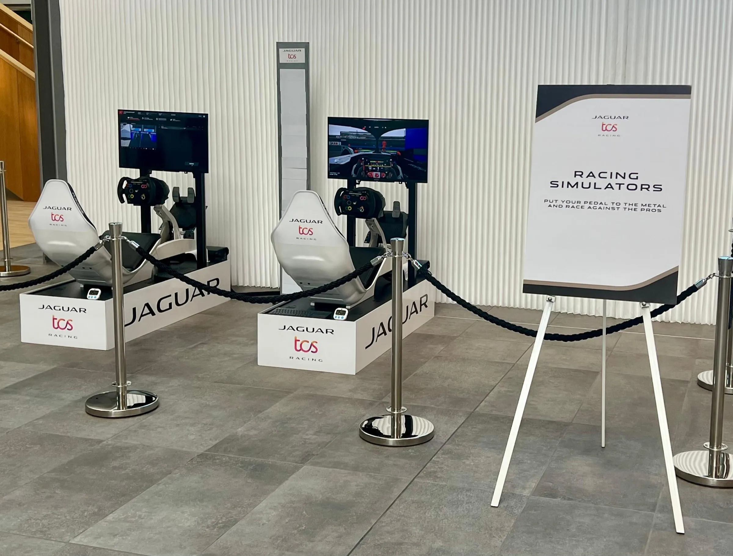Two Jaguar TCS Racing branded simulators next to a racing simulators sign