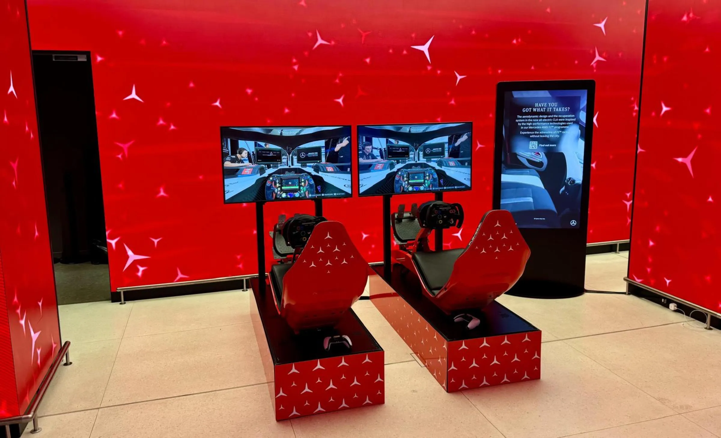 Two Mercedes branded simulators in front of a full red LED wall at a corporate event